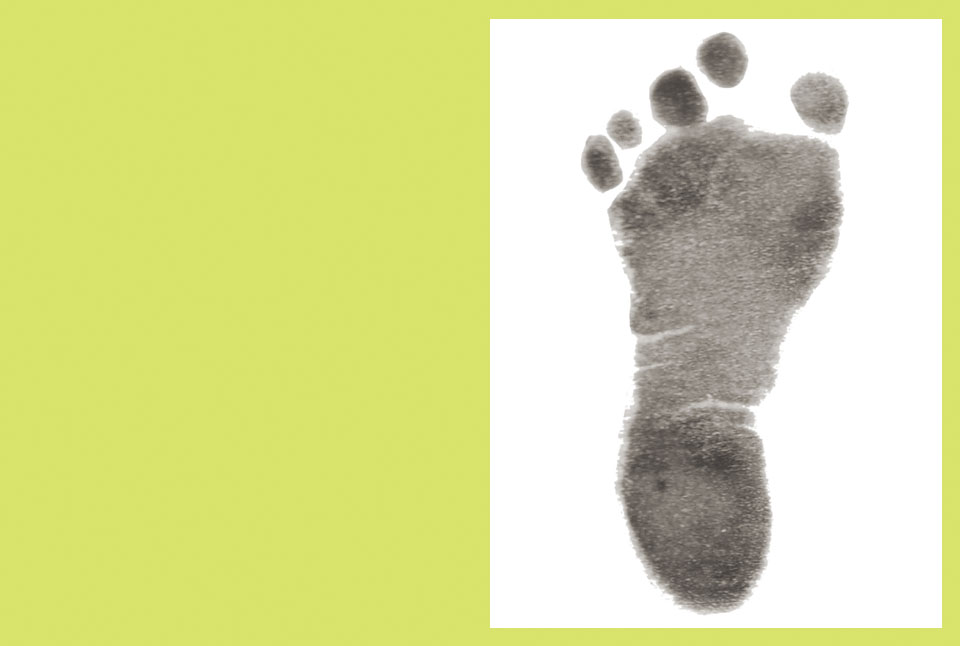 Close-up of a soft gray ink footprint stamped on white paper with a yellow-green border, simple minimal mood